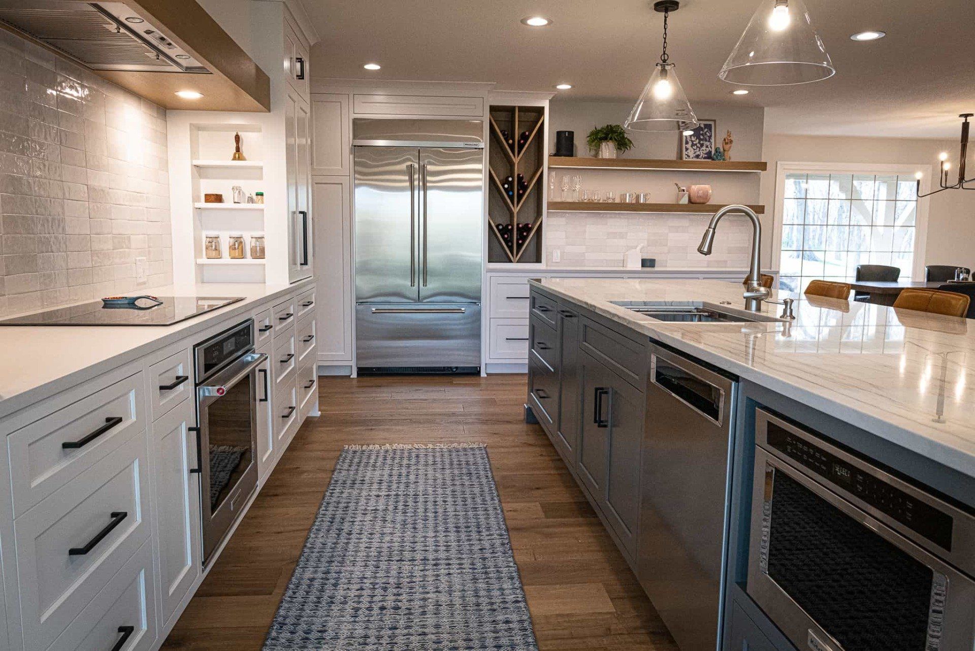 Modern kitchen with white cabinets, stainless steel appliances, a custom wine rack and abundant natural light