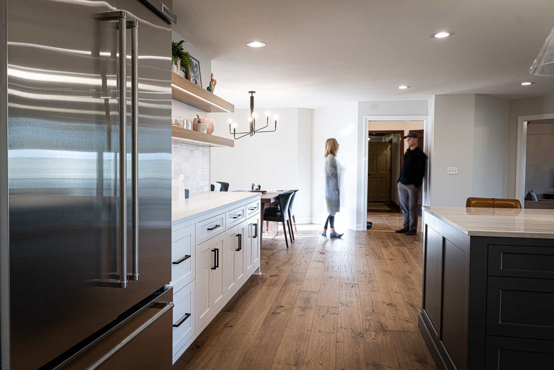 Stainless steel refrigerator, white cabinets, and a kitchen island