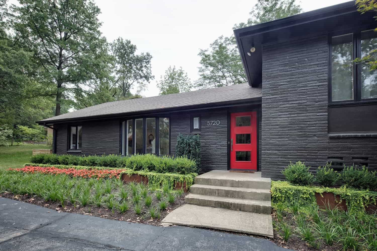 Exterior view of mid-century modern home with dark siding and bright red door