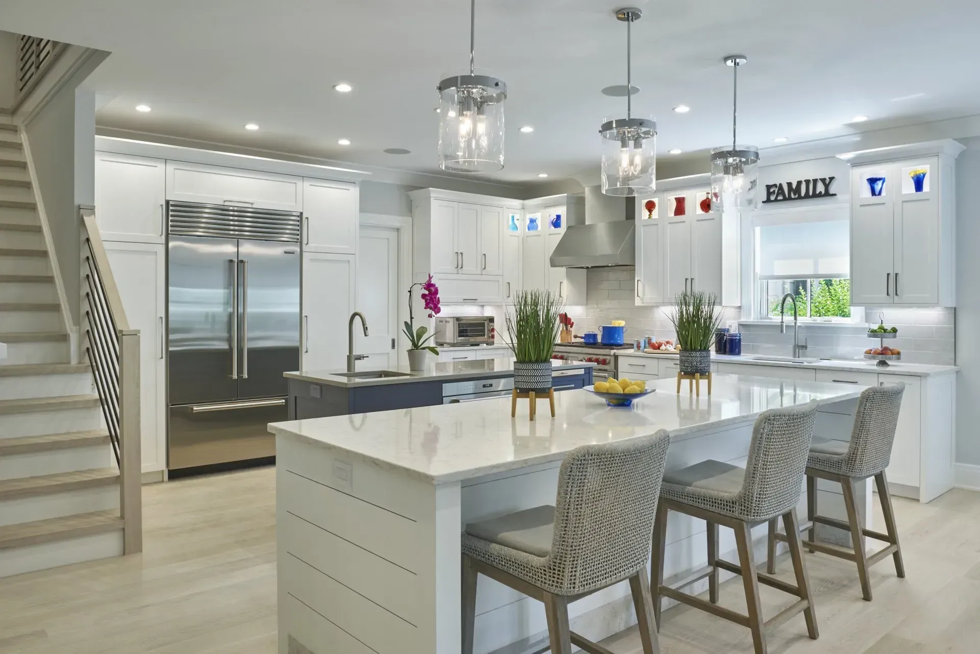 Modern white kitchen with island, stainless steel appliances, and wood flooring.