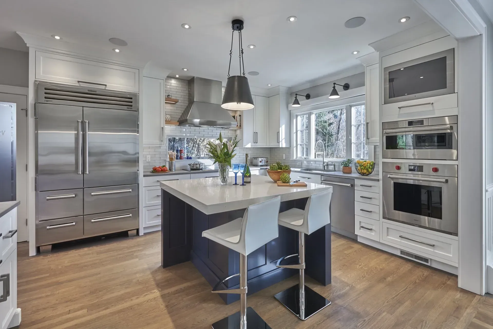 Modern kitchen with stainless steel appliances, blue island, and light wood flooring.