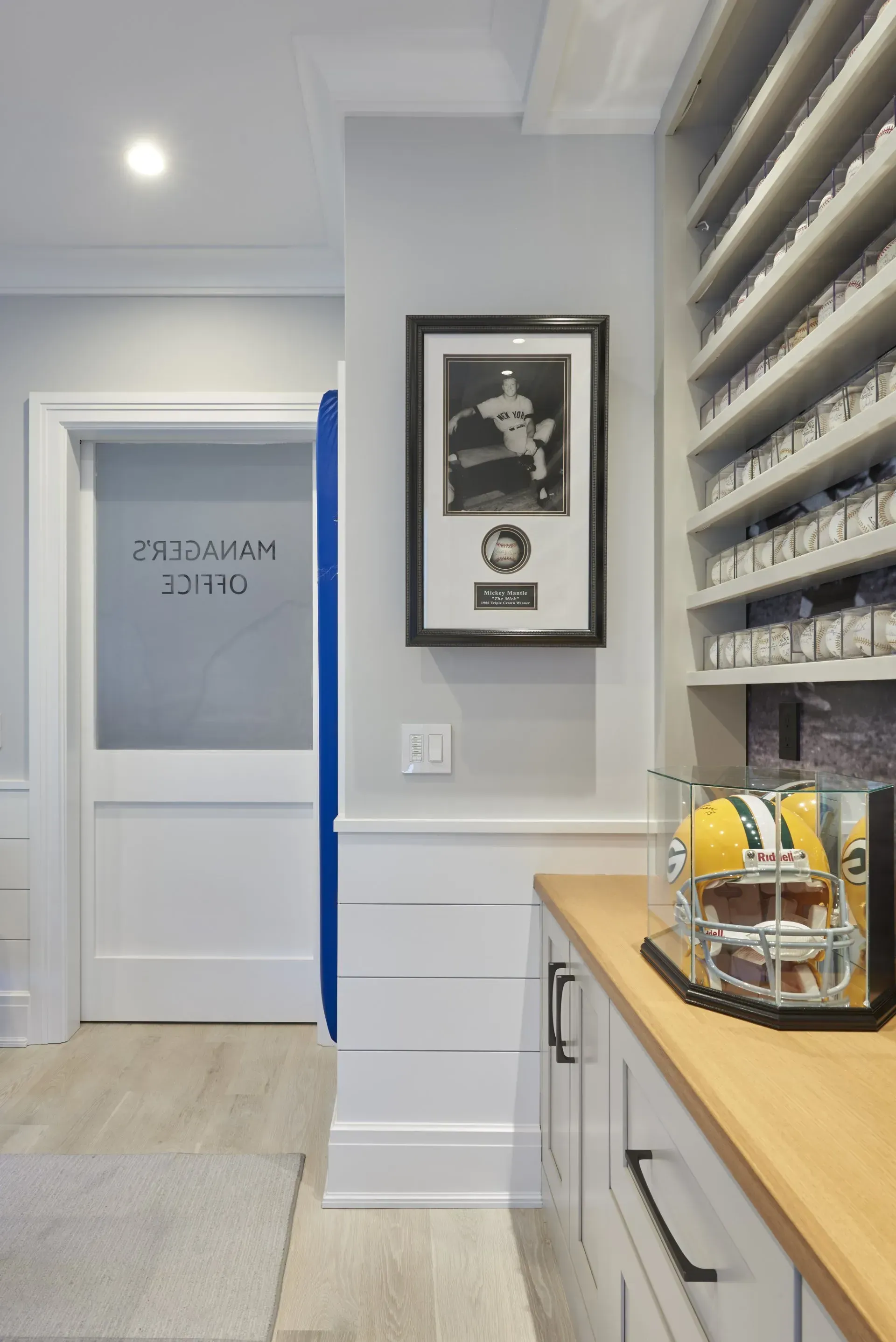 Office area with framed photo, cabinets, and a football helmet on a counter.