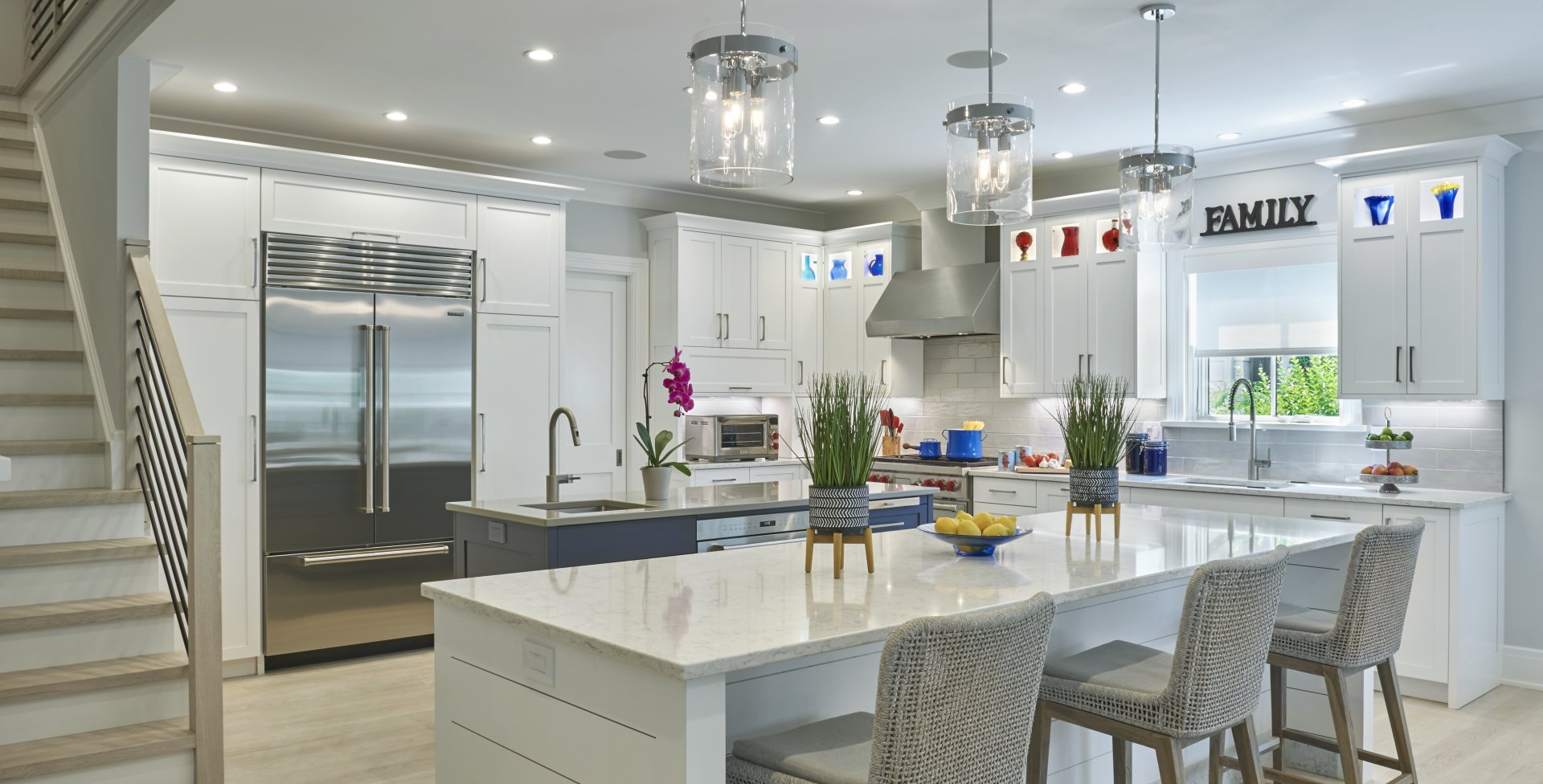 Bright, modern kitchen with white cabinets, stainless steel appliances, and a large island with bar stools.