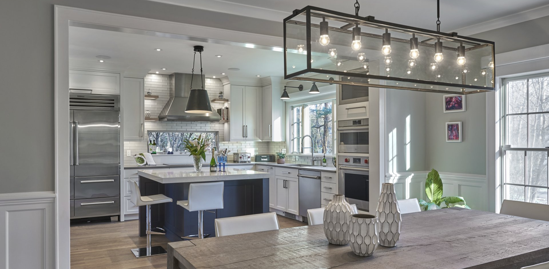 Kitchen interior with island, dining table, and large glass-enclosed light fixture.
