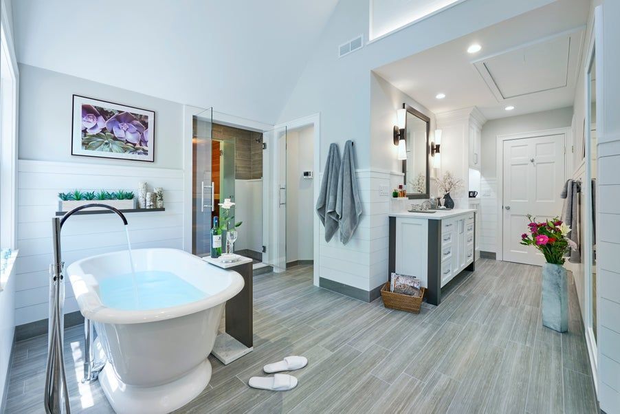 Spacious, modern bathroom with a soaking tub, vanity, and walk-in shower. Light blue walls, gray floors, and white accents.