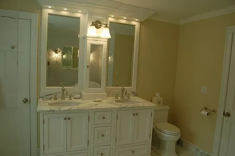 White bathroom vanity with two sinks, mirrors, and a toilet. Yellow walls and white trim.