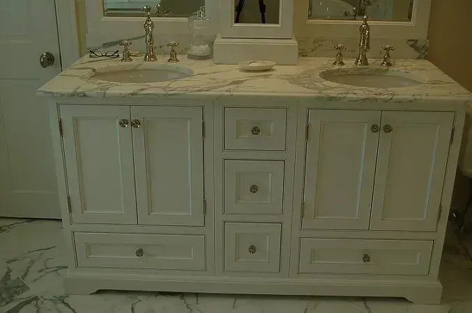 White double sink vanity with marble top, cabinets, and drawers in a bathroom.