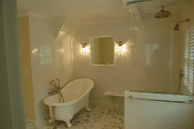 Bathroom with clawfoot tub, tiled walls, and glass shower.