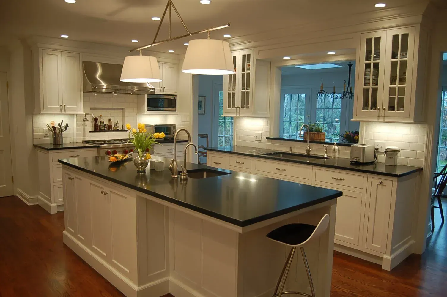 White kitchen with black countertops, two islands, and a window overlooking a green yard.