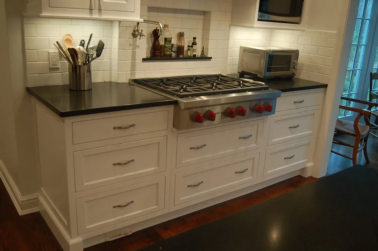 White kitchen cabinets with a black countertop and a gas stove.