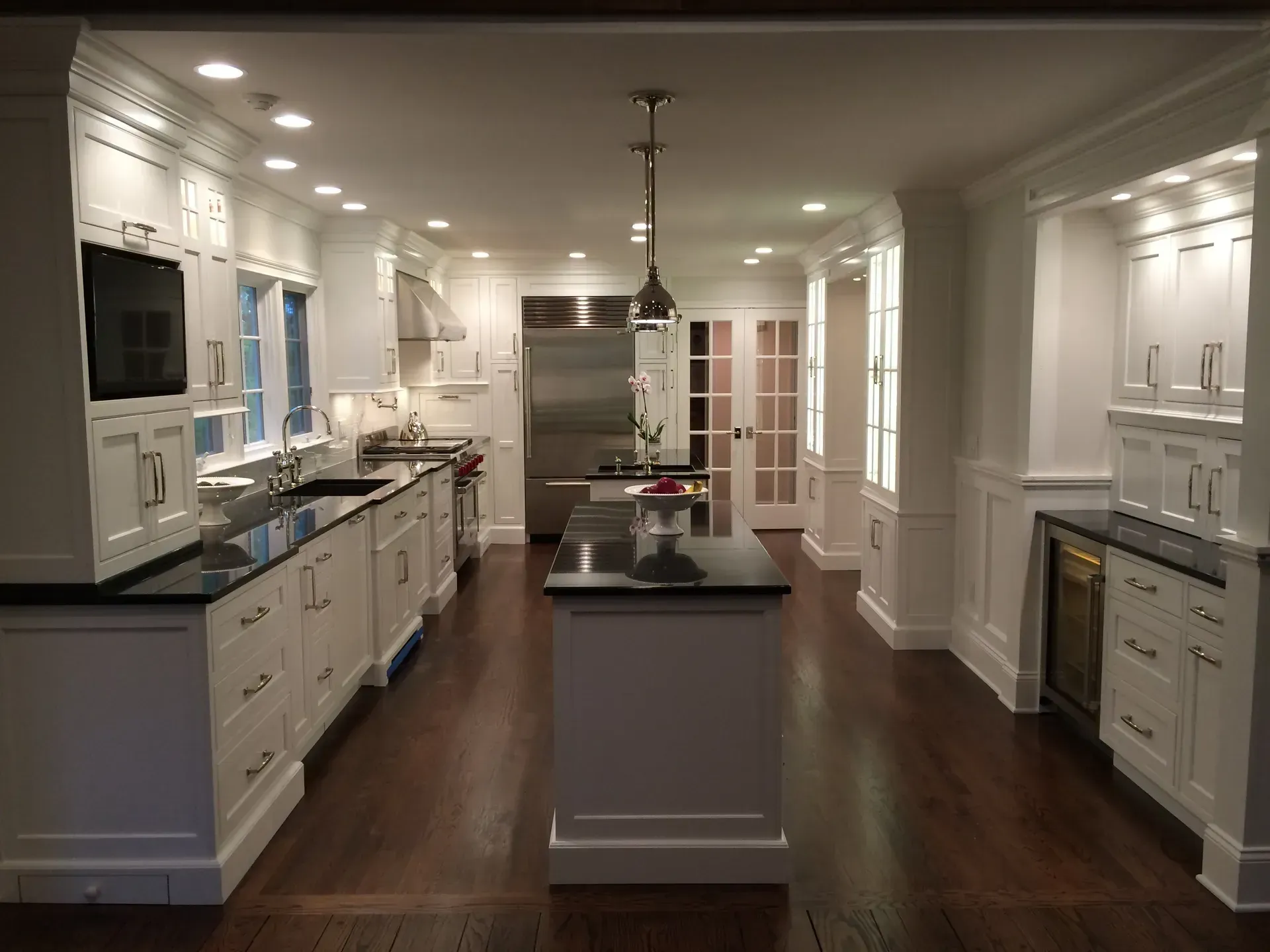 White kitchen with black countertops, stainless steel appliances, and dark wood floor.