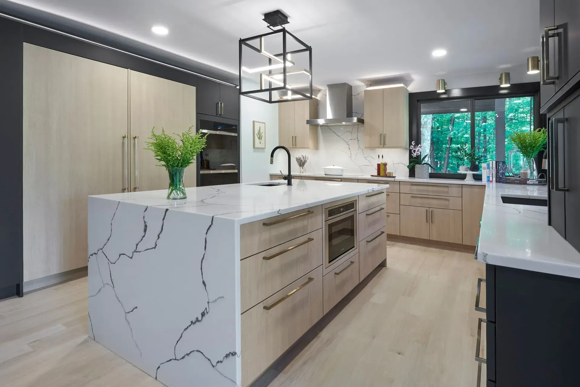 Modern kitchen with large island, light wood cabinets, dark gray walls, and bright white countertops.