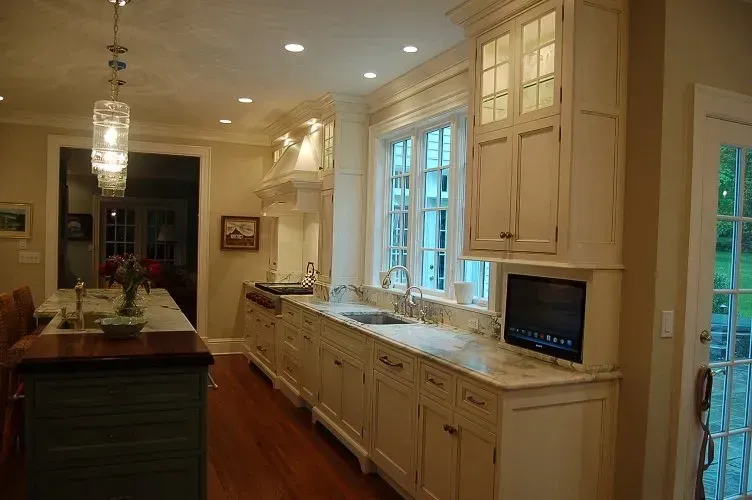 Spacious kitchen with cream cabinets, granite counters, wooden floor, and a window overlooking a yard.