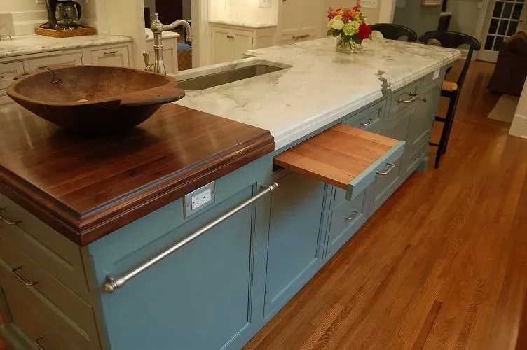 Kitchen island with a wooden countertop and a sink; teal cabinets, pull-out table.