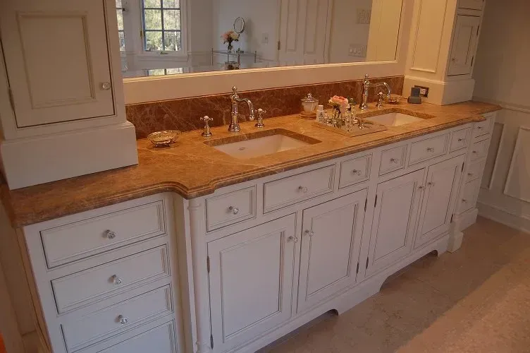 White bathroom vanity with two sinks, marble countertop, and built-in cabinets.