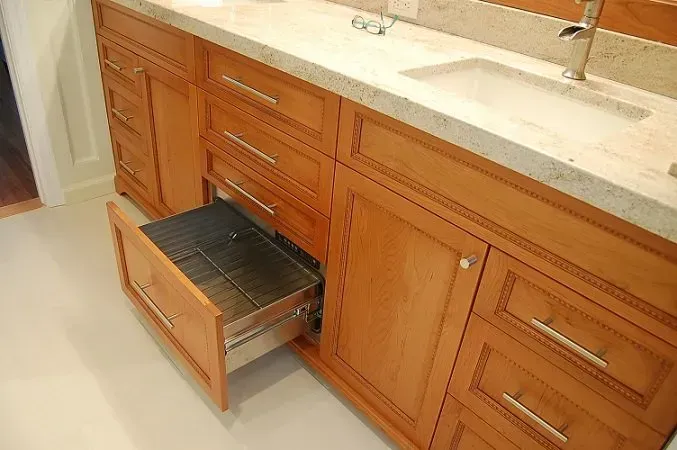 Wooden bathroom vanity with an open drawer, a sink, and a countertop.