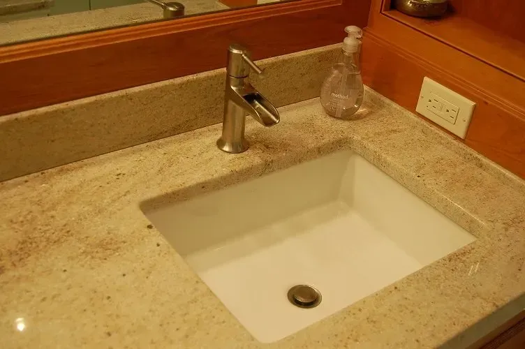 Bathroom sink with a granite countertop, faucet, and soap dispenser.