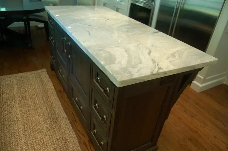 Kitchen island with dark cabinetry, light countertop, and a wooden floor.