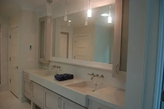 Bathroom with double sink vanity, large mirror, and recessed lighting. Light-colored cabinetry and walls.