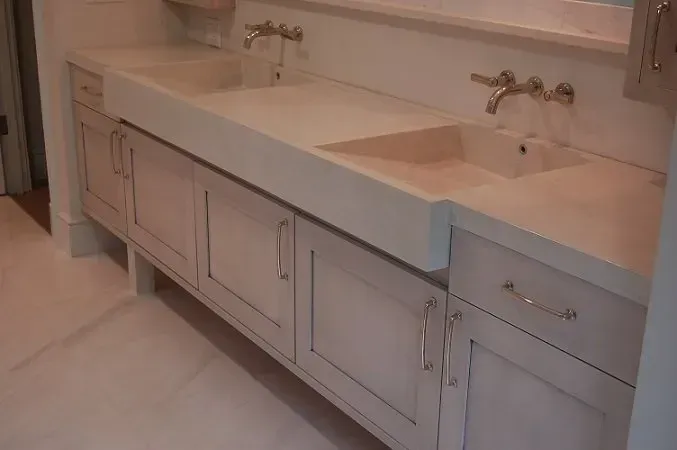Light-colored vanity with two sinks, gold fixtures, and pale cabinets in a bathroom.