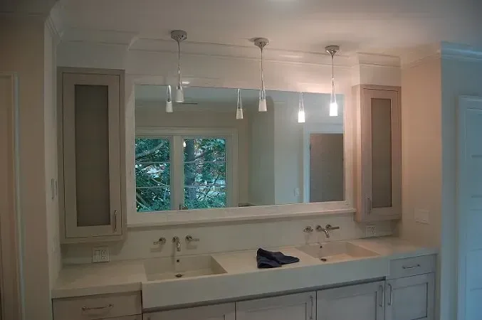 Bathroom with white cabinets, a large mirror, and pendant lights.