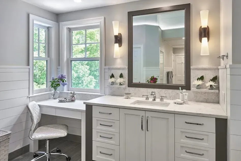 Bathroom with white vanity, window, mirror, and sconces; neutral color palette.