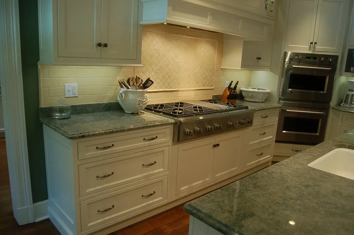 White kitchen with a stove, double oven, and granite countertops.