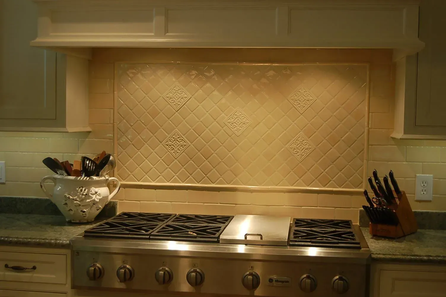 Kitchen with stainless steel stove, beige tile backsplash, and cabinets.