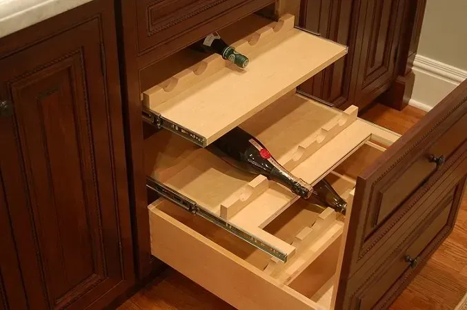 Wooden cabinet with pull-out shelves holding wine bottles. Dark brown finish. Interior view.