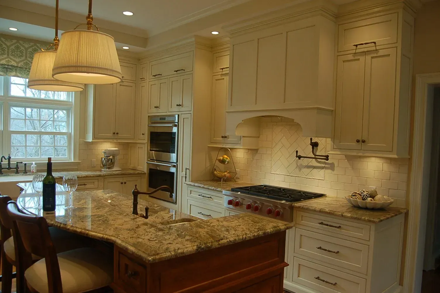 Cream-colored kitchen with granite countertops, wooden island, double oven, stove, and pendant lighting.
