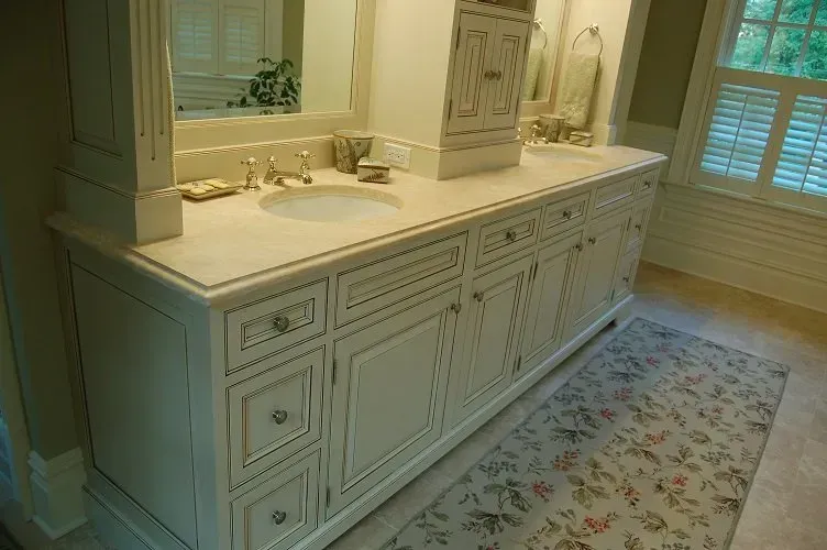 White bathroom vanity with drawers and cabinets, a sink, and a floral rug.