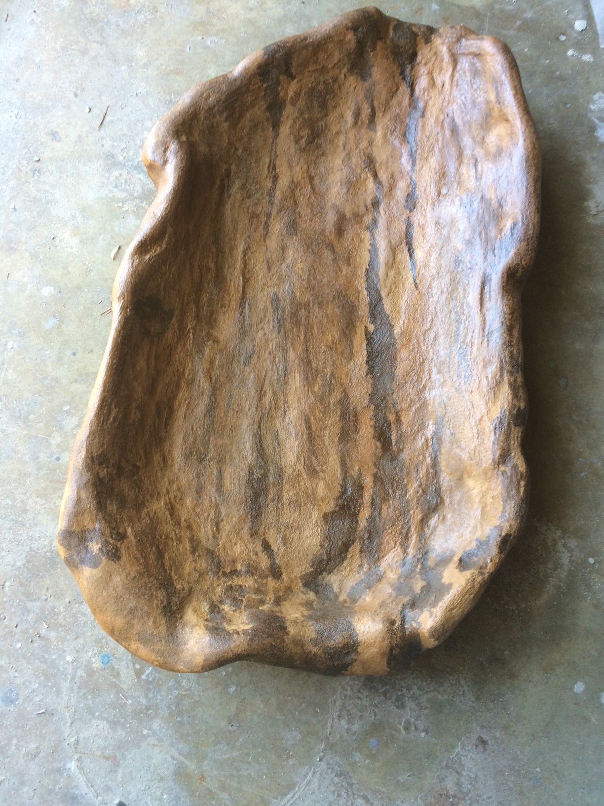 A large piece of wood is sitting on a concrete surface.