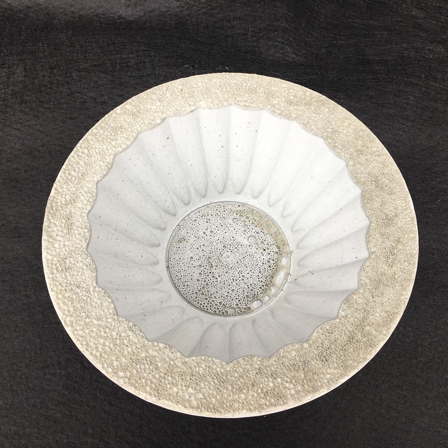 A white plate with a gold rim sits on a black surface