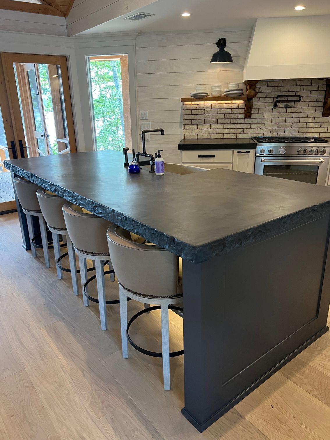 A kitchen with a large island and a lot of chairs.