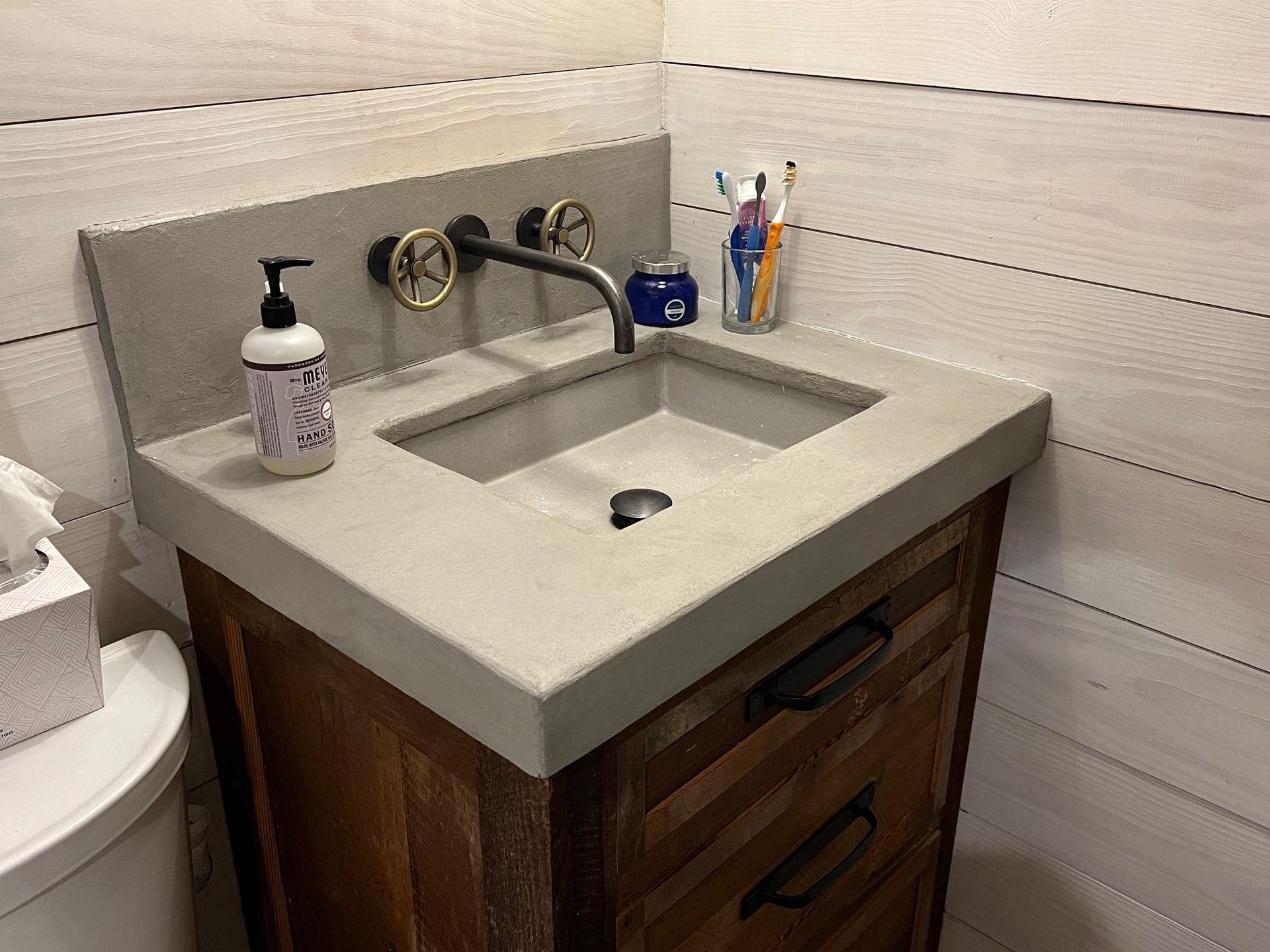 A bathroom sink with a soap dispenser and toothbrushes on it.