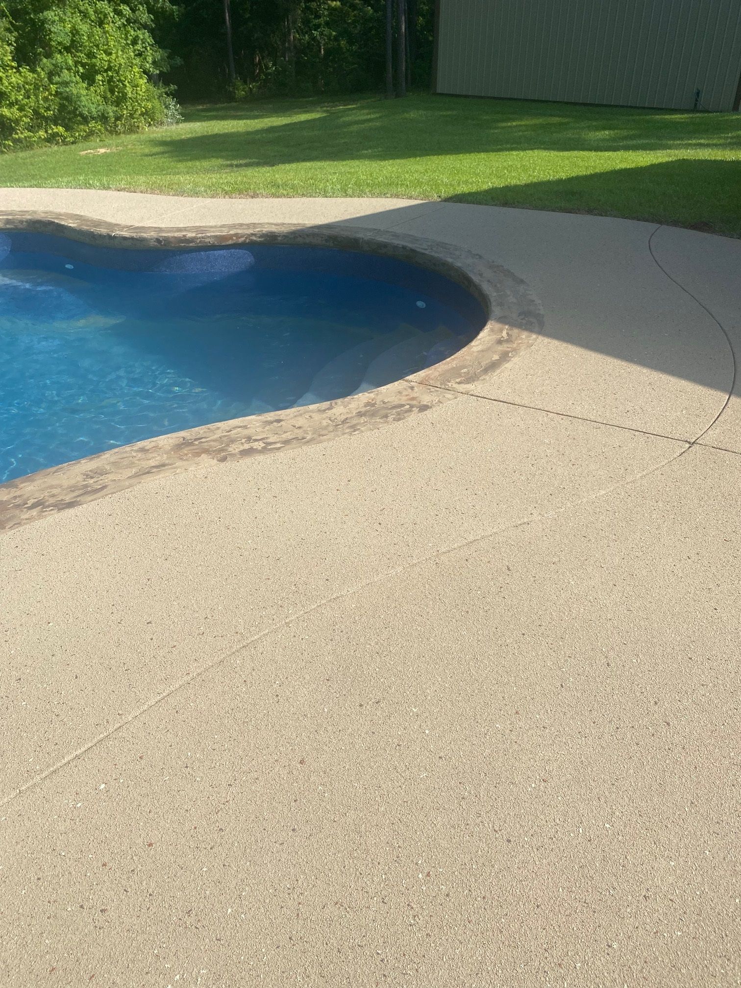 A swimming pool with a concrete deck next to it.
