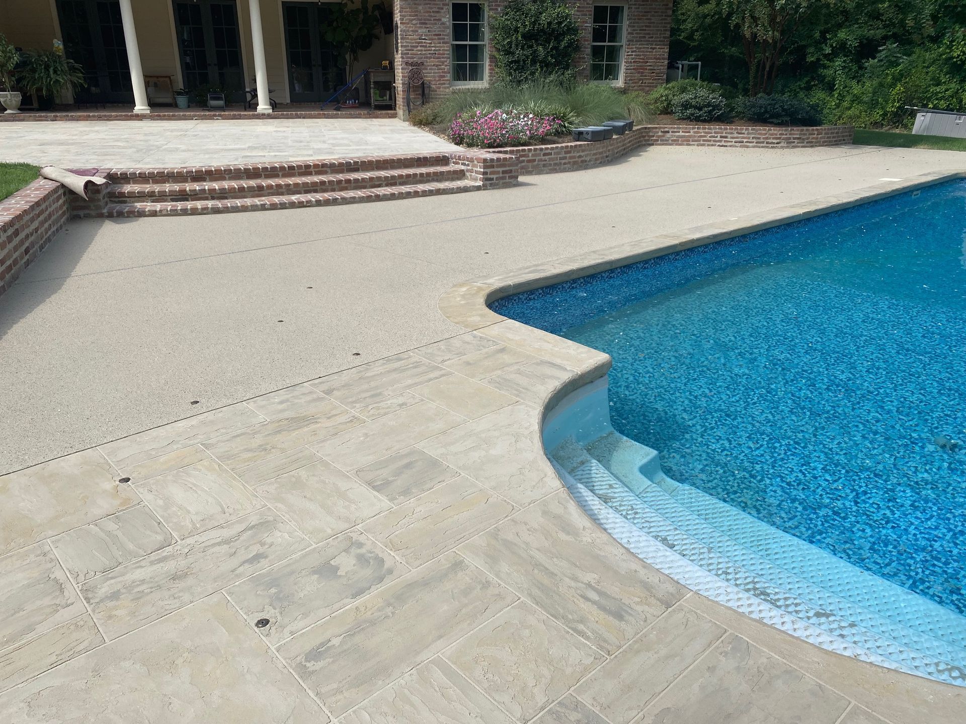 A large swimming pool with a patio in front of it