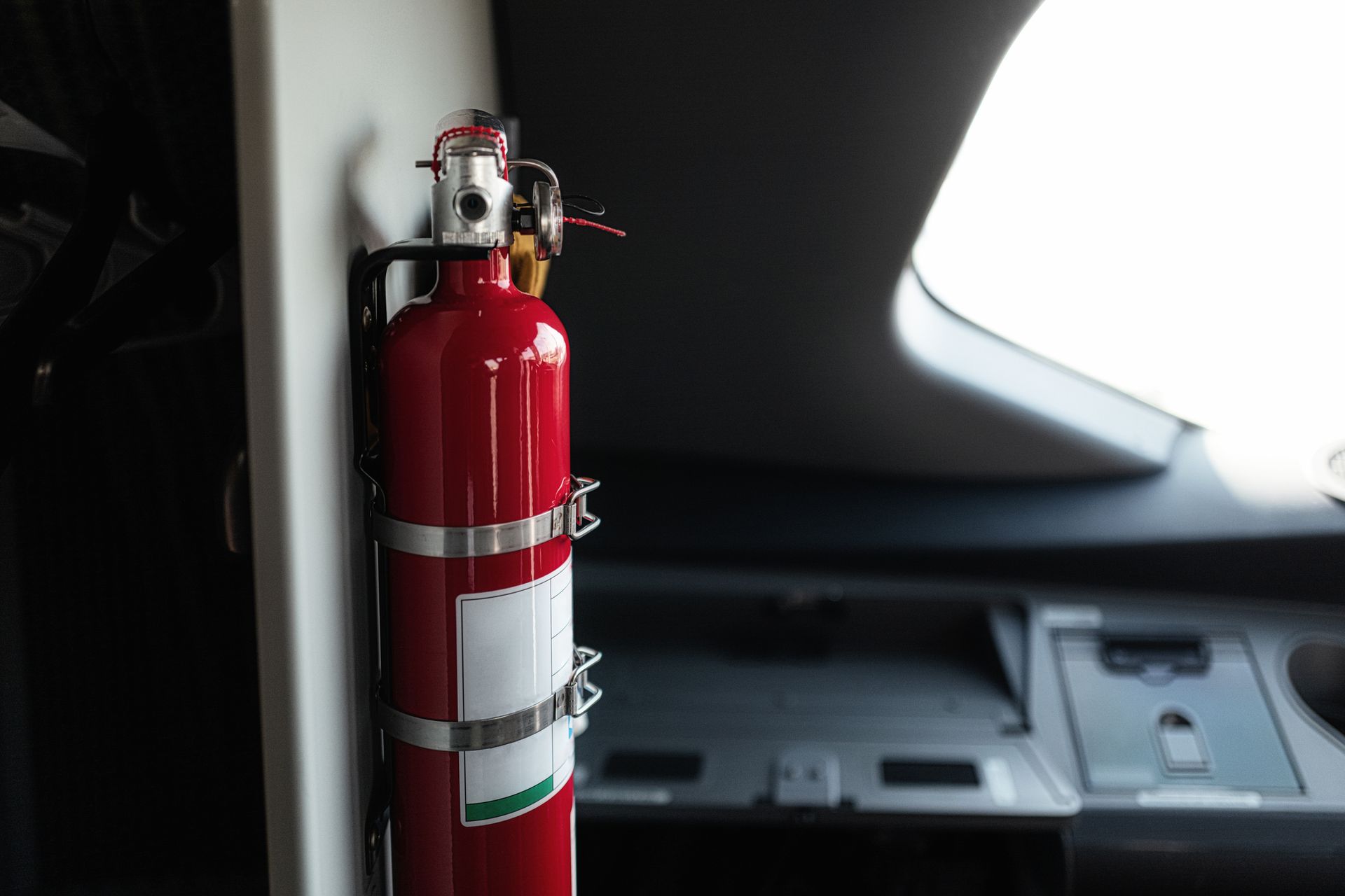 A red fire extinguisher is hanging on a wall in a car.