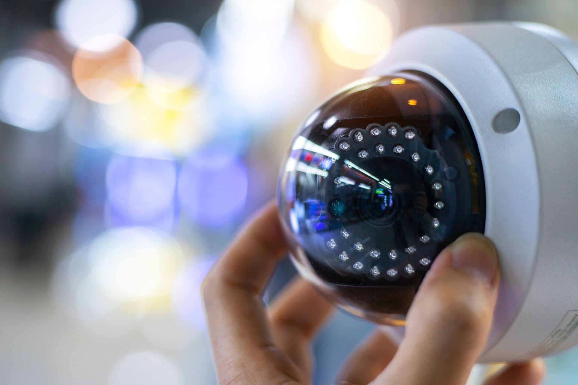 A person is holding a security camera in their hand.