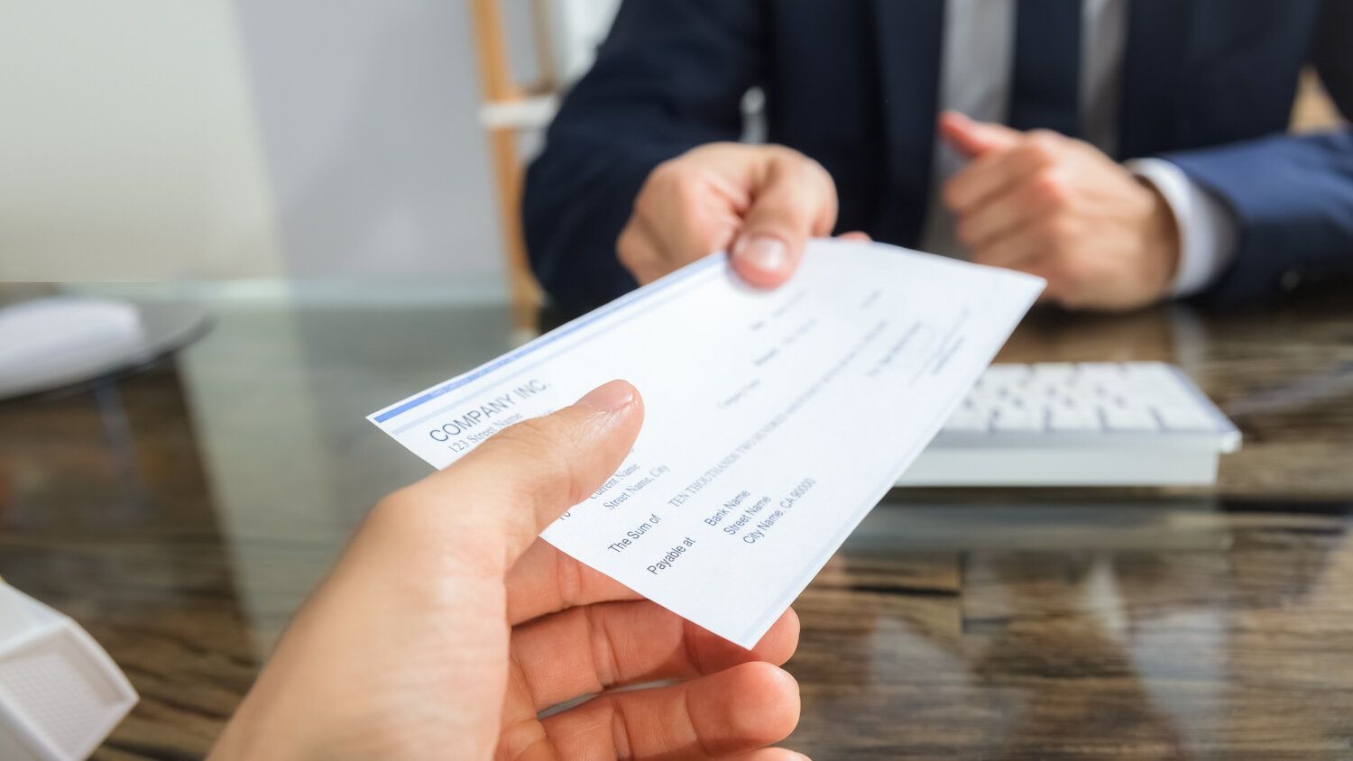 A person is handing a check to another person.