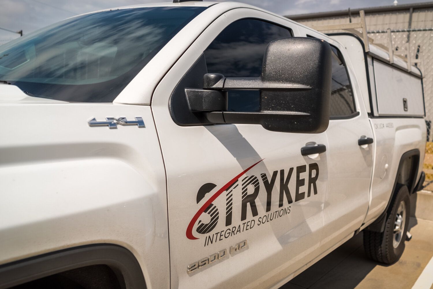A white truck with the word stryker on the side is parked in a parking lot.