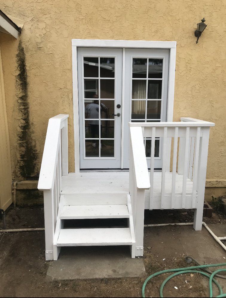 White wooden porch steps and ramp leading to a glass patio door on a yellow stucco house.