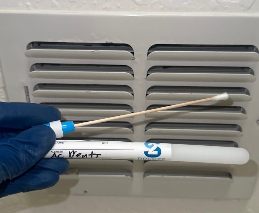 Certified technician collecting a mold swab sample from an air vent
