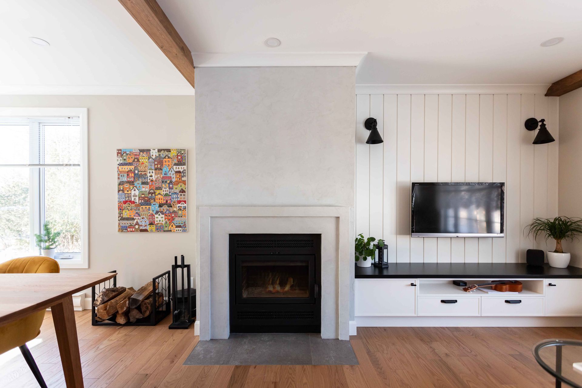 Cheminée moderne avec cheminée noire contre un mur texturé, à côté d'un mur en panneaux sombres avec une télévision.