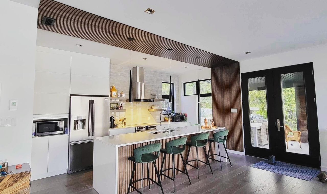 Cuisine moderne avec armoires blanches, comptoirs en marbre, tabourets de bar verts et accents en bois.