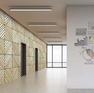 Couloir avec mur géométrique en bois, ascenseurs et graphiques commerciaux sur un mur blanc.