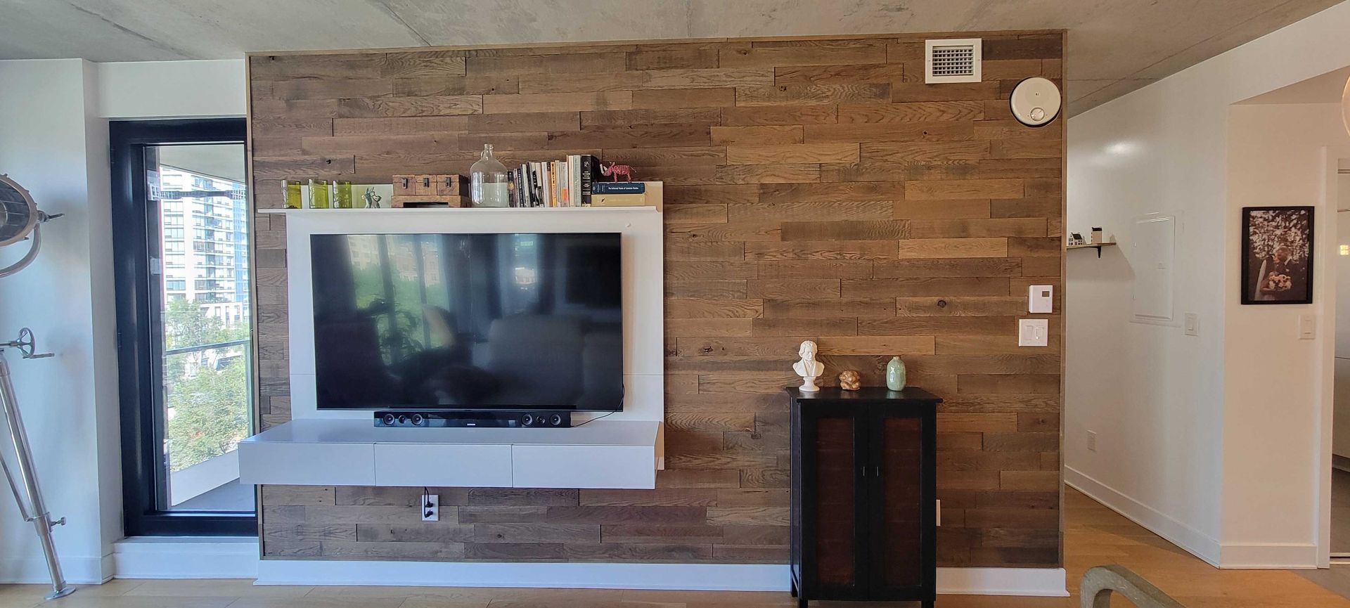 Canapé et fauteuil roses devant un mur lambrissé de bois, avec une table basse en marbre et une grande plante d'intérieur.