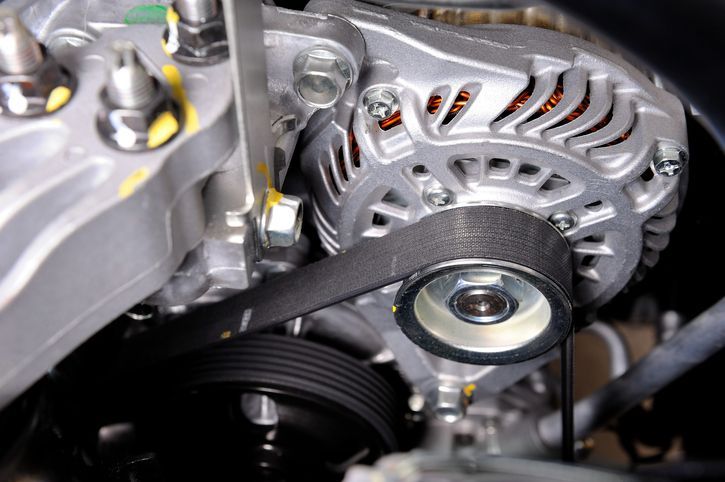 Close-up of a belt on a silver car engine, inside an engine room.
