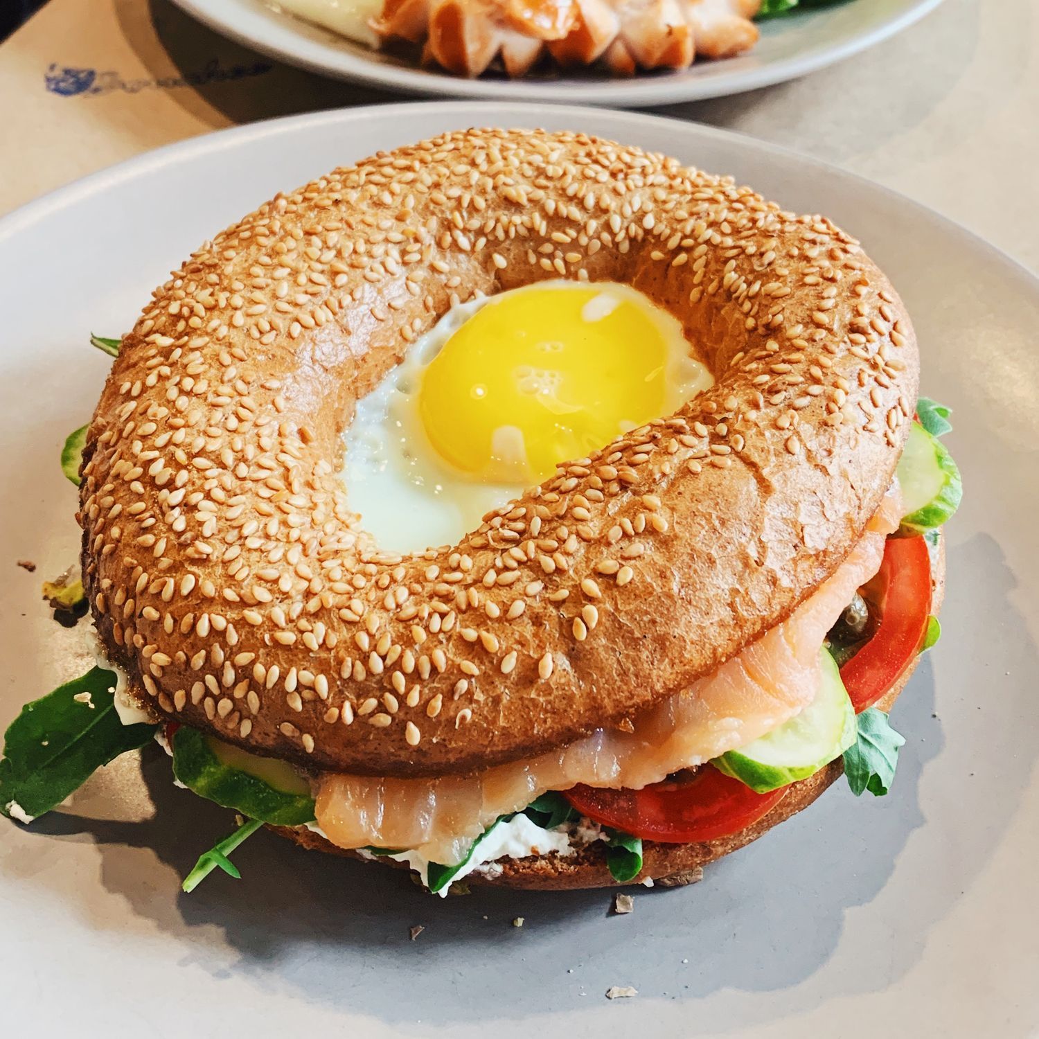 A bagel with eggs tomatoes and lettuce on a plate