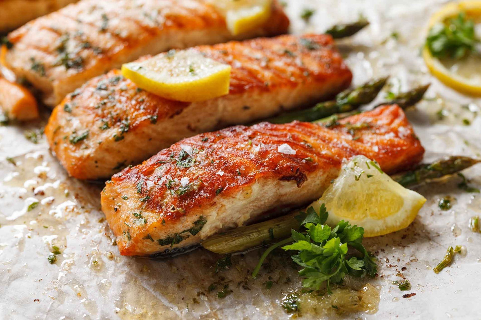 A close up of a plate of food with salmon and asparagus on a table.